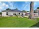 Home's rear exterior showcasing a well-maintained lawn, solar panels, and a charming deck, ideal for outdoor living at 1020 N Orange Ave, Orange City, FL 32763