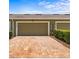 Two-car garage with brick paver driveway, green siding, green door, and decorative bushes at 10460 Burrows St, Orlando, FL 32832