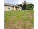 Spacious backyard with a covered patio, lush lawn, and mature trees at 1115 Adirondack St, Deltona, FL 32725