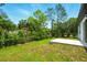 A grassy backyard with a small concrete pad, chain link fence, and mature trees at 1161 Kenway Ave, Deltona, FL 32738