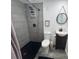 Modern bathroom features a walk-in shower with gray tiling, a toilet, and a vanity with a round mirror at 1215 N Boston Ave, Deland, FL 32724