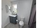 Bright bathroom features a single vanity with a gray cabinet, toilet, and walk-in shower with a curtain at 1215 N Boston Ave, Deland, FL 32724