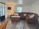 Comfortable living room featuring a brown sectional sofa, wood floors, and a sliding glass door feature at 1215 N Boston Ave, Deland, FL 32724