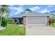 Charming single-story home with well-maintained landscaping, a blue and brick facade, and an attached two-car garage at 123 Wood Ibis Ct, Daytona Beach, FL 32119