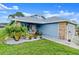 Charming single-story home with a well-manicured lawn, blue siding, and beautiful tropical landscaping at 123 Wood Ibis Ct, Daytona Beach, FL 32119