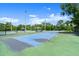 Well-maintained tennis court featuring a blue and green surface, surrounded by fencing and trees at 123 Wood Ibis Ct, Daytona Beach, FL 32119