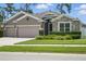 Inviting single-story home featuring a stone-accented facade, three-car garage, and landscaped front yard at 1314 Lake Baton Dr, Deltona, FL 32725