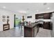 Modern kitchen features dark cabinetry, stainless steel appliances and kitchen island with tile flooring at 136 Columbia Dr, Kissimmee, FL 34759