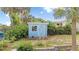 Cute light blue shed with white trim nestled among lush greenery and palm trees in the backyard at 1420 N Grandview Ave, Daytona Beach, FL 32118