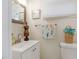 Cozy half-bath with a white vanity, nautical decor, and a decorative mirror at 1455 Whitewood Dr, Deltona, FL 32725
