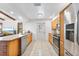 Bright kitchen area showcasing a stainless steel refrigerator, wooden cabinets, and a door to the outside at 1660 E Apache Cir, Deltona, FL 32725