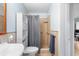 Light and bright bathroom with wood framed mirror, tile shower, and over the toilet cabinet at 1702 Palmetto Ave, Deland, FL 32724