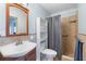 Light and bright bathroom with wood framed mirror, vanity, and tile shower with curtain at 1702 Palmetto Ave, Deland, FL 32724