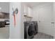 Well-lit laundry room with front-load Samsung washer and dryer, white cabinets, and coat hooks by the entry to the kitchen at 1846 N Acadian Dr, Deltona, FL 32725