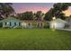 Charming home with lush front lawn, mature trees, and inviting curb appeal at dusk at 204 Rio Pinar Dr, Ormond Beach, FL 32174
