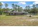 Charming brick home with a chain-link fence and mature trees, set against a beautiful sky at 2620 Doyle Rd, Deltona, FL 32738