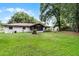 Backyard view of home and lush landscaping featuring mature trees, a firepit, and a spacious lawn at 270 Sandyhook Ln, Deland, FL 32724