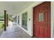 Inviting front porch featuring a vibrant red front door and rustic wood flooring at 2950 Ragis Rd, Edgewater, FL 32132