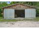Large garage with sliding metal doors showcasing ample storage space for vehicles and equipment at 2950 Ragis Rd, Edgewater, FL 32132
