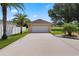 Detached garage with a wide driveway, landscaping, and palm trees on a sunny day at 3 Pine Meadow Ct, Debary, FL 32713
