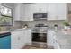 Well-lit kitchen featuring stainless steel appliances, white cabinets, and light wood flooring at 3117 Pine Tree Dr, Edgewater, FL 32141