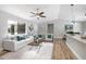 Bright living room featuring white furniture, hardwood floors, a ceiling fan, and an open connection to the kitchen at 3117 Pine Tree Dr, Edgewater, FL 32141