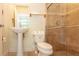 Well-lit bathroom with a pedestal sink, toilet, and tile shower with glass door at 3428 Longleaf Rd, Ormond Beach, FL 32174