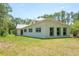 Exterior of the light yellow house with green trim, showcasing the side and back of the property with large lawn at 3428 Longleaf Rd, Ormond Beach, FL 32174