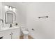 Modern half bathroom with black hardware, a white vanity and a uniquely arched mirror at 3655 Scott St, Port Orange, FL 32129