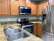 Modern kitchen featuring stainless steel appliances, warm wood cabinetry, and neutral countertops at 405 Carina Cir, Sanford, FL 32773