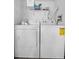 Laundry room equipped with a white washer and dryer, plus overhead storage shelves at 4403 Sea Mist Dr # 2110, New Smyrna Beach, FL 32169