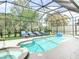 Inviting in-ground pool with poolside lounge chairs in a screened enclosure at 456 Sea Duck Dr, Daytona Beach, FL 32119