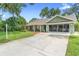 Exterior view of home with long driveway, green grass and screened in garage at 552 Hamlet Dr, Port Orange, FL 32127