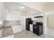 Bright kitchen featuring white cabinets, tile backsplash, and efficient black appliances at 5825 Forest Grove Blvd, Orlando, FL 32808