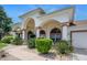 Elegant home featuring a grand arched entrance, lush landscaping, and manicured walkway at 6083 Sabal Hammock Cir, Port Orange, FL 32128
