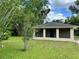 Single story home with neutral toned paint and green lawn surrounded by trees at 632 W Hubbard Ave, Deland, FL 32720