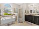 Bathroom featuring a soaking tub, glass enclosed shower, dual sink vanity, and natural light at 727 Grape Ivy Ln, New Smyrna Beach, FL 32168