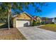 Garage of yellow single story home with driveway and well-maintained landscaping at 727 Grape Ivy Ln, New Smyrna Beach, FL 32168