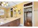 Bright bathroom featuring double sinks, decorative lighting, and an open doorway to a bedroom with hardwood floors at 762 Onyx Pkwy, Deland, FL 32724