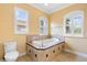 Bathroom featuring a large soaking tub, toilet, tile floors, and natural light from windows at 762 Onyx Pkwy, Deland, FL 32724