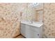 Bathroom with white vanity, sink, framed mirror, leaf wallpaper, and beige tile flooring at 8 Rising Moon Trl, Ormond Beach, FL 32174