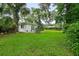 Secluded backyard with lush lawn, mature trees, and patio, ideal for relaxation at 812 Faulkner St, New Smyrna Beach, FL 32168
