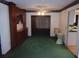 Open-concept living room with built-in cabinets and green carpet, leading to the kitchen at 871 Oak Tree Ln, Lake Helen, FL 32744