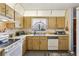 Cozy kitchen featuring wood cabinets, a window with a decorative curtain, and essential appliances at 903 Deer Springs Rd, Port Orange, FL 32129