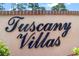Elegant Tuscany Villas signage displayed on a stucco wall, surrounded by lush greenery enhancing the community's appeal at 118 Tuscany Villas Dr, Edgewater, FL 32141