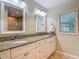 Bathroom featuring double sinks, granite countertops, and white cabinetry with natural light from the window at 1516 Arrowhead Trl, Enterprise, FL 32725