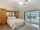 Serene main bedroom offers wood-look floors, a built-in headboard, and sliding door access to the lanai at 1516 Arrowhead Trl, Enterprise, FL 32725