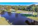An aerial view showcases a serene pond with a charming dock and a covered picnic area surrounded by lush trees at 1516 Arrowhead Trl, Enterprise, FL 32725