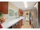 Well-lit laundry room with cherrywood cabinets, white counters, stainless fridge, and tile flooring at 1555 Mercers Fernery Rd, Deland, FL 32720