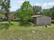 A gray outbuilding is situated in a grassy yard with trees, adding functional charm to the property at 1555 Mercers Fernery Rd, Deland, FL 32720